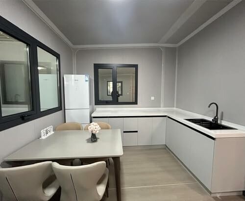 Modern kitchen with white cabinets, sink, and dining table.